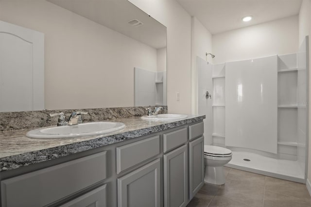 bathroom featuring tile patterned flooring, vanity, a shower, and toilet