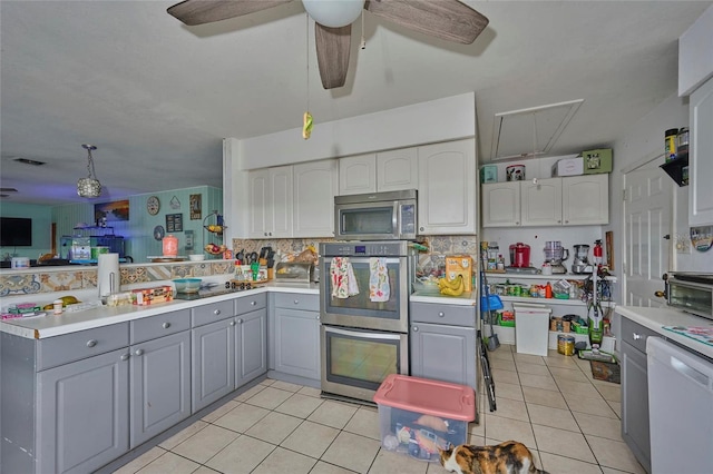 kitchen with light tile patterned floors, appliances with stainless steel finishes, gray cabinets, ceiling fan, and backsplash