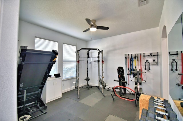 exercise room with ceiling fan and a textured ceiling