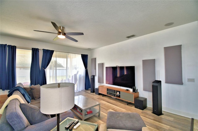 living room with a textured ceiling, light hardwood / wood-style floors, and ceiling fan