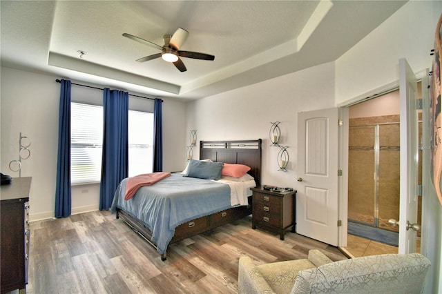 bedroom with a tray ceiling, ceiling fan, and hardwood / wood-style flooring