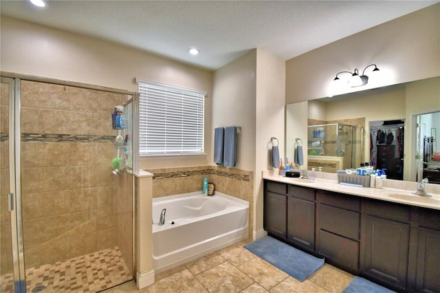 bathroom featuring tile patterned flooring, vanity, a textured ceiling, and plus walk in shower