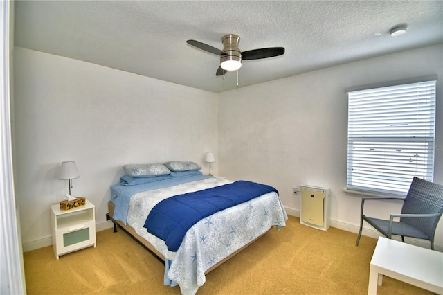 bedroom with ceiling fan, light carpet, and a textured ceiling