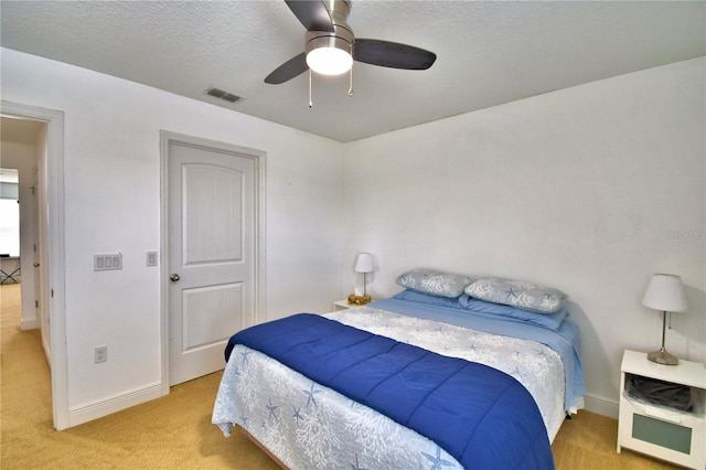 carpeted bedroom featuring ceiling fan and a textured ceiling