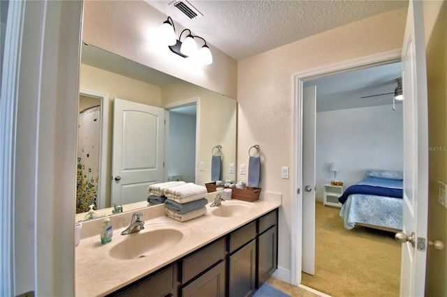 bathroom with vanity, ceiling fan, and a textured ceiling