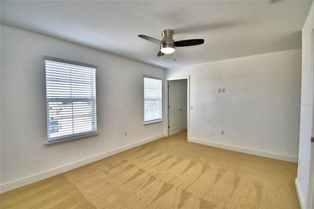 spare room with ceiling fan, light colored carpet, and a textured ceiling