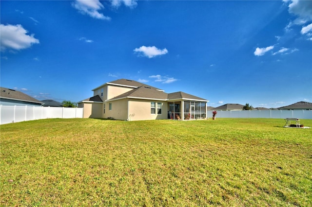 rear view of house featuring a yard and a sunroom