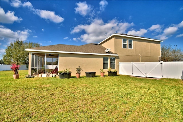 rear view of house featuring a lawn and a sunroom