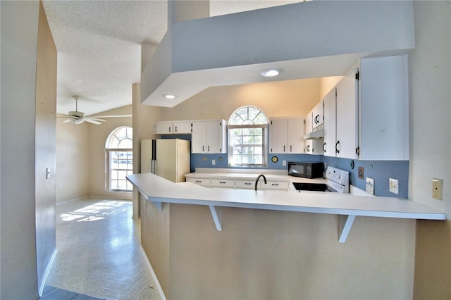 kitchen with range with electric stovetop, white cabinetry, white refrigerator, kitchen peninsula, and plenty of natural light