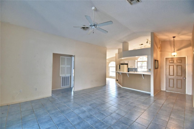 unfurnished living room featuring lofted ceiling, tile patterned floors, and ceiling fan