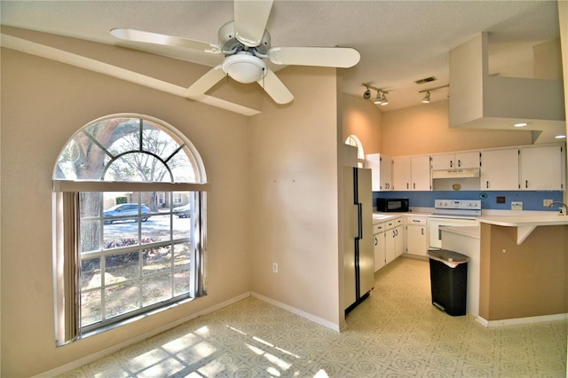 kitchen with a healthy amount of sunlight, track lighting, white cabinets, and white appliances