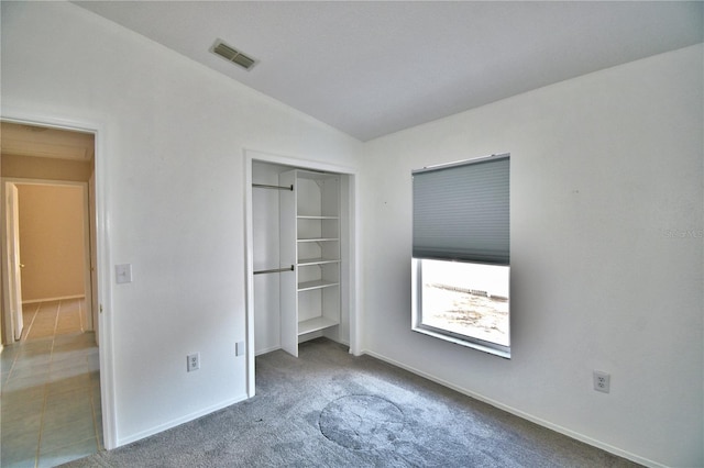 unfurnished bedroom with carpet floors, a closet, and vaulted ceiling