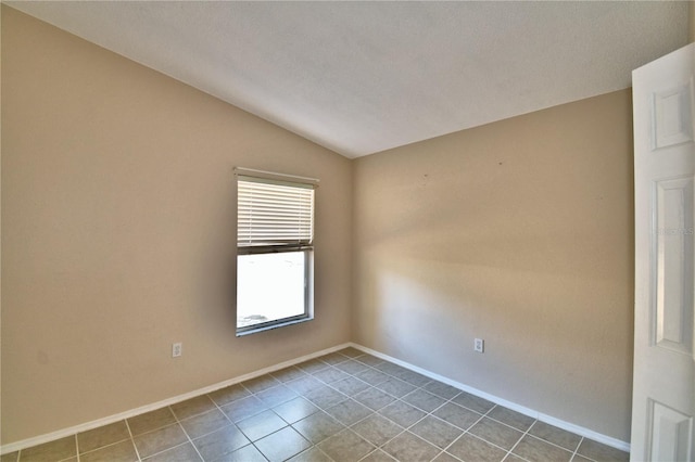 tiled empty room featuring vaulted ceiling