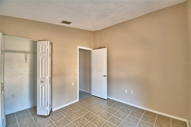 unfurnished bedroom featuring tile patterned flooring, a closet, and a textured ceiling