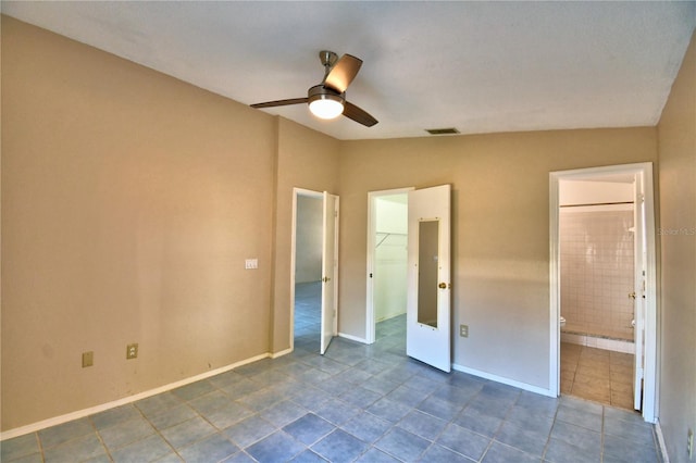 unfurnished bedroom with ceiling fan, ensuite bathroom, vaulted ceiling, and a walk in closet