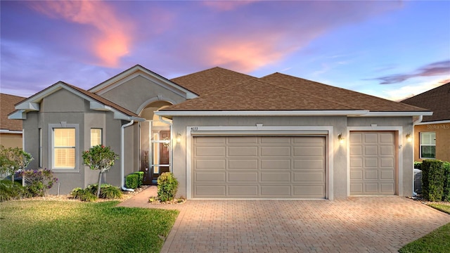 single story home featuring a garage and a lawn