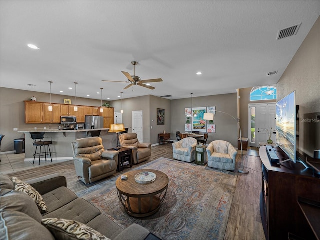 living room featuring a textured ceiling, light hardwood / wood-style floors, and ceiling fan