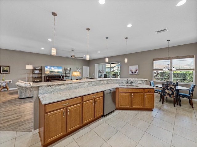 kitchen featuring light stone counters, hanging light fixtures, sink, and dishwasher