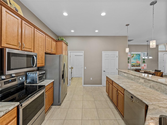 kitchen with appliances with stainless steel finishes, light tile patterned floors, light stone counters, and decorative light fixtures