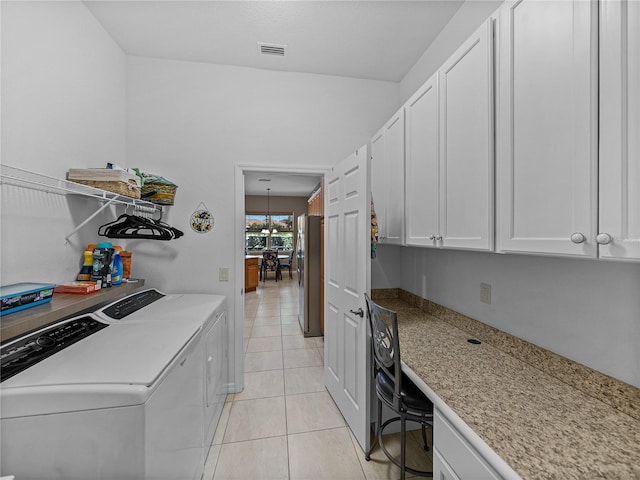 laundry area with light tile patterned floors, cabinets, and washing machine and clothes dryer