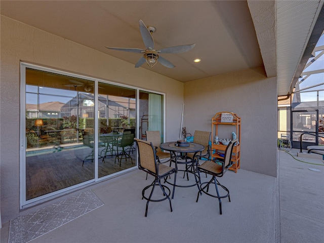 view of patio featuring ceiling fan and glass enclosure