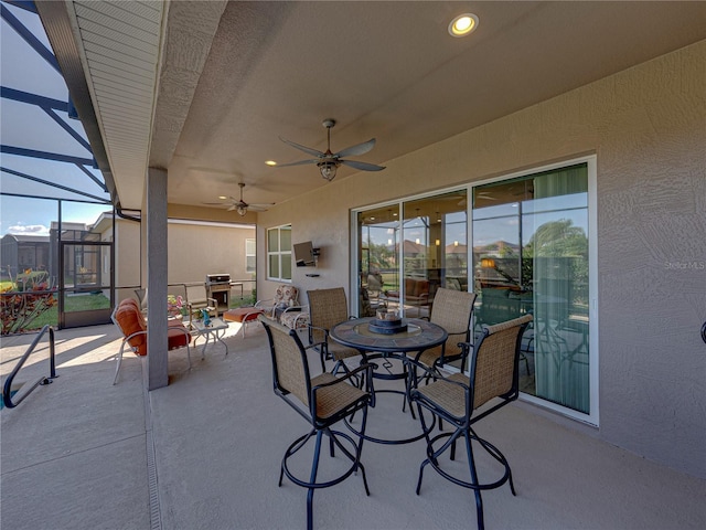 view of patio with grilling area, ceiling fan, and glass enclosure