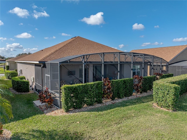 back of property with a yard and glass enclosure