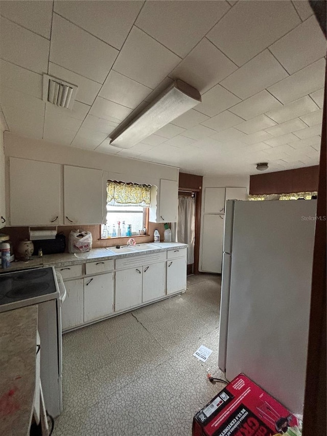 kitchen featuring white cabinetry, sink, stainless steel refrigerator, and electric stove