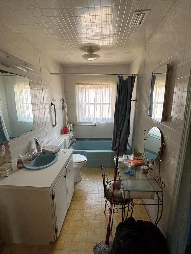 full bathroom with tile walls, vanity, shower / bath combo, and toilet