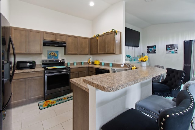 kitchen with sink, a breakfast bar, black appliances, light tile patterned flooring, and kitchen peninsula