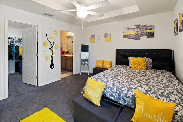 carpeted bedroom with ensuite bath, ceiling fan, a raised ceiling, a spacious closet, and a closet