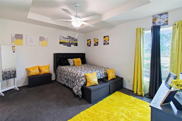 bedroom with dark carpet, a raised ceiling, and ceiling fan