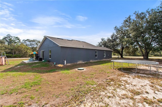 view of side of property featuring a yard, a patio, and a trampoline