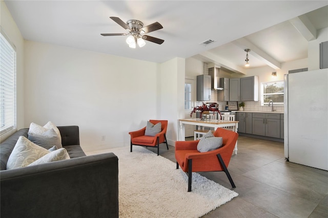 living room with ceiling fan, sink, and beam ceiling