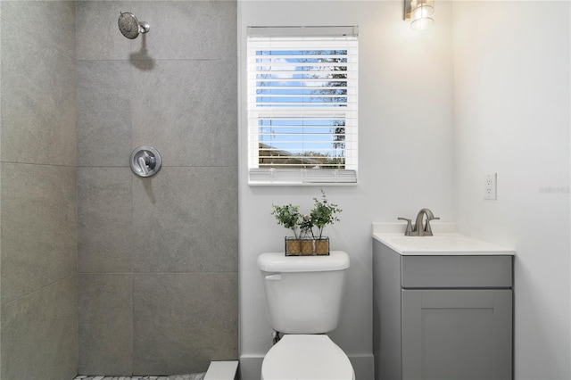 bathroom with vanity, toilet, and a tile shower