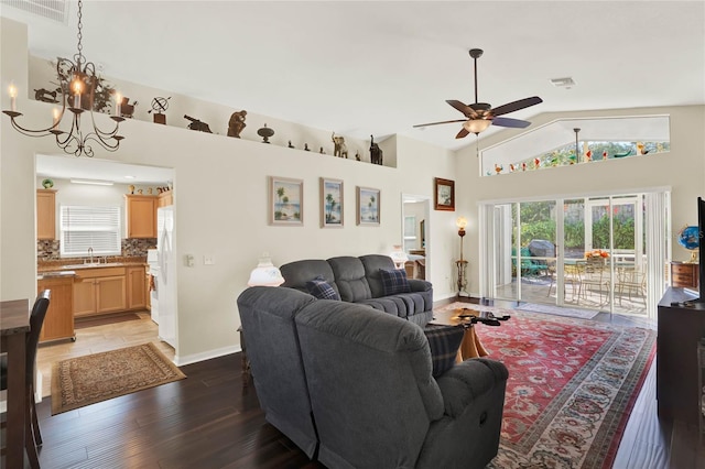 living room with ceiling fan with notable chandelier, sink, hardwood / wood-style floors, and high vaulted ceiling