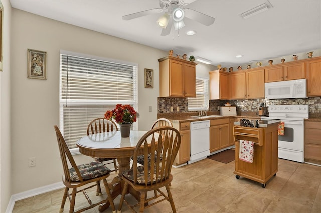 kitchen with sink, white appliances, a kitchen island, ceiling fan, and backsplash