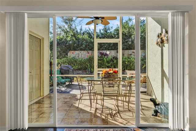 doorway to outside with ceiling fan and tile patterned floors