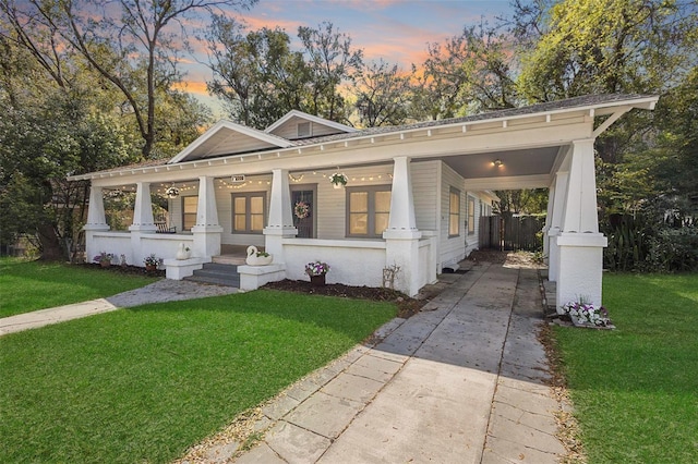 view of front of home with covered porch, driveway, a front lawn, and a carport