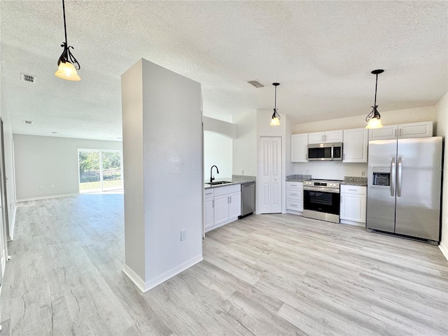 kitchen with sink, white cabinetry, hanging light fixtures, light wood-type flooring, and appliances with stainless steel finishes