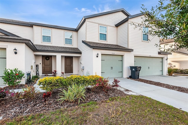 townhome / multi-family property featuring a garage, a shingled roof, concrete driveway, and stucco siding