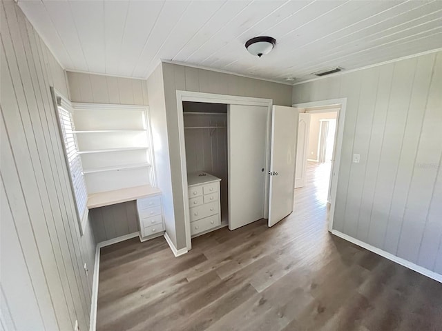 unfurnished bedroom featuring hardwood / wood-style flooring, built in desk, and a closet