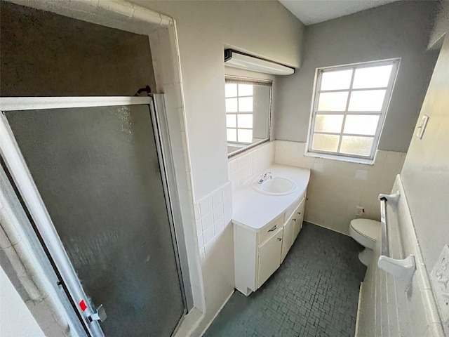 bathroom with vanity, toilet, tile walls, and walk in shower