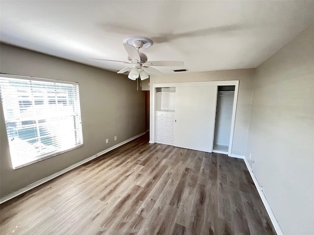 unfurnished bedroom featuring ceiling fan, wood-type flooring, and a closet