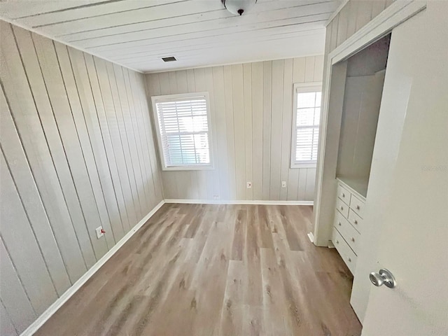 unfurnished bedroom with light wood-type flooring and wooden walls