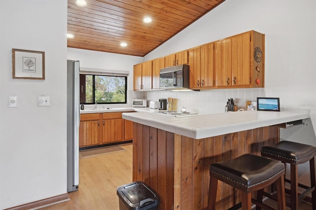 kitchen with a kitchen breakfast bar, decorative backsplash, vaulted ceiling, wooden ceiling, and kitchen peninsula