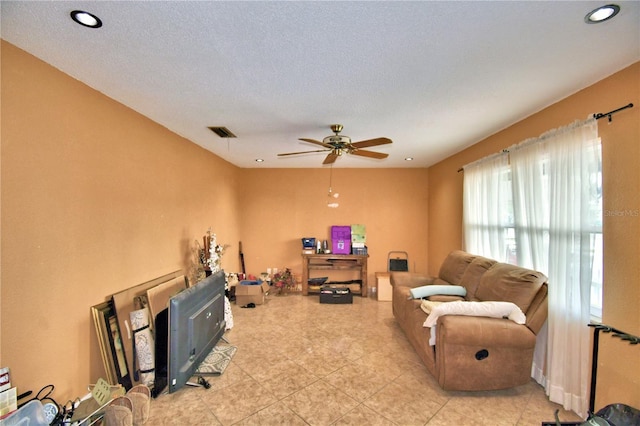 living room with ceiling fan and a textured ceiling