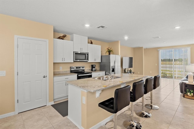 kitchen with stainless steel appliances, a breakfast bar area, a center island with sink, and white cabinets