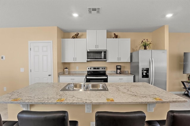 kitchen featuring sink, stainless steel appliances, and a center island with sink