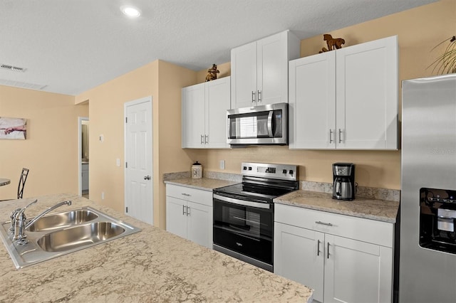 kitchen with white cabinetry, appliances with stainless steel finishes, sink, and a textured ceiling